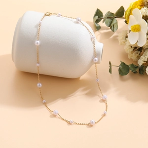 Detail of vintage pearl choker on a white vase with golden chain and elegant pearls