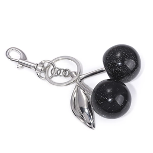 Close-up of black cherry keychain with silver leaves and sparkling glitter texture