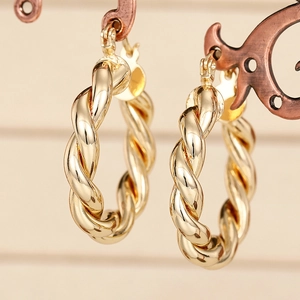 Goldene geflochtene Creolen mit poliertem Metall-Finish auf einem Schmuckständer