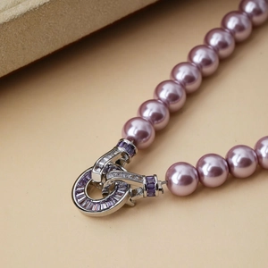 Macro shot of purple pearl necklace with silver pavé clasp and rectangular crystals