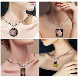 Detail van vierkante hars ketting met roze droogbloemen en zwart koord