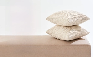 Detail of two beige corduroy pillow covers with textured fabric on a wooden bench