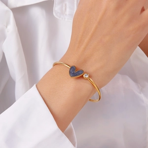 Detail of golden heart bangle with blue marble texture and crystal on wrist