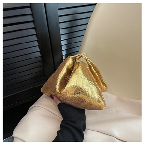 Gros plan d'une pochette à paillettes dorées tenue sur un fond minimaliste chic