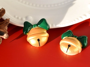 Macro view of gold festive Christmas bell ornaments with green bows on red background