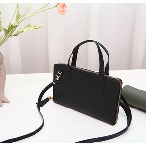 Close-up of black cross-grain leather bag featuring gold hardware and fringe detail