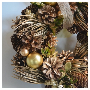 Detailed close-up of a Christmas wreath with gold baubles, pine cones and green needles