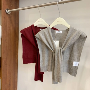 Premium wool knit shawls in dark red and grey displayed on hangers in a studio
