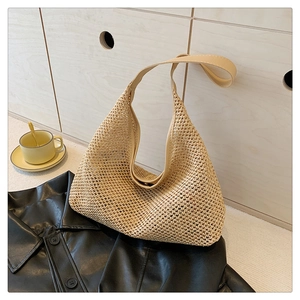 Detail of woven khaki tote bag on black leather jacket with leather shoulder strap