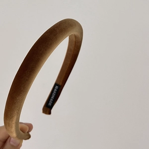 Detail of a brown velvet padded headband featuring a handmade woven label inside