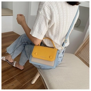 Detail of crossbody bag showing ginger yellow flap and grey panel on model