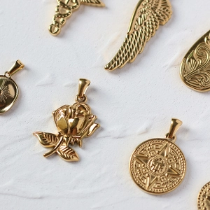 Close-up of gold titanium rose, wings, and coin pendants for DIY jewelry design