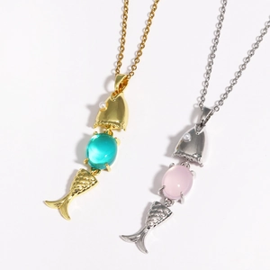 Detail of fish bone necklaces with green and pink gems on a white background