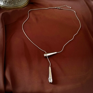 Detailed view of silver water drop pendant on a sleek snake chain lariat necklace