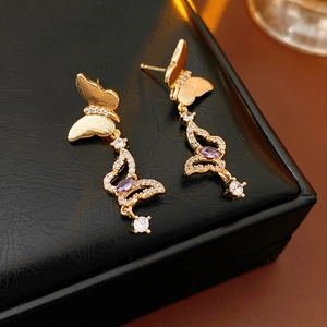 Detail of vintage golden butterfly earrings with purple zircon and sparkling crystals