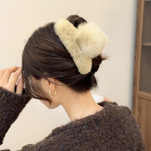 Detail view of a plush cream-colored faux fur hair claw clip for elegant autumn hairstyles