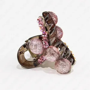 Detailed macro view of hair claw with pink rhinestone embellishments and gold spring mechanism