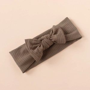 Detailed view of brown ribbed knit baby headband featuring a knotted bow accent
