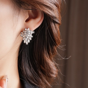 Close-up of sparkling floral leaf stud earrings with pavé crystals on a model's ear