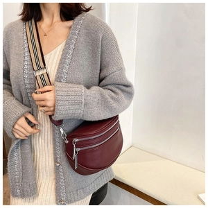 Detail of burgundy lychee leather crescent crossbody bag with wide striped shoulder strap