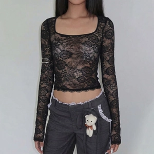 Détail d'un haut noir en dentelle à manches longues avec motifs ajourés sur un mannequin