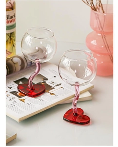 Detail of unique wine glasses featuring curved stems and red heart shaped bases