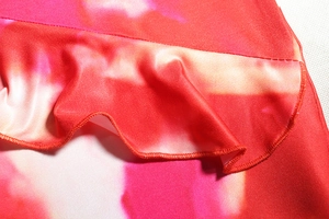 Detailed close-up of vibrant red and pink floral print fabric with ruffled edges