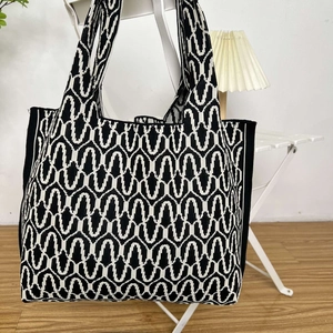 Detail of knitted tote bag showing black and white wave geometric pattern on thick fabric