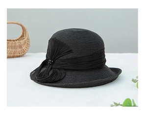 Détail du chapeau de paille noir élégant avec un nœud chic et des accents de perles fines