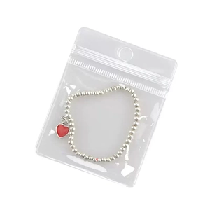 Silver beaded bracelet with red heart pendant in transparent PVC self-sealing jewelry bag