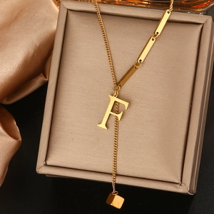 Detail van gouden titanium stalen F-letter hanger ketting op luxe sieradendoos