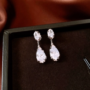 Macro detail of silver drop earrings with zircon crystals on premium black jewelry box