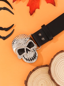 Détail de boucle crâne argentée avec strass sur ceinture punk noire sur fond orange