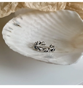 Detailed view of an S925 sterling silver hollow heart ring placed on a decorative seashell