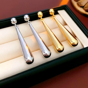 Close-up of gold and silver teardrop drop earrings in a black jewelry box display