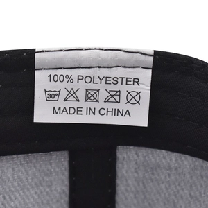 Detail view of the white care label on 100% polyester cap showing washing symbols