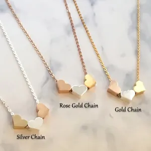 Detailed shot of triple heart pendant necklaces in silver, rose gold, and gold on marble