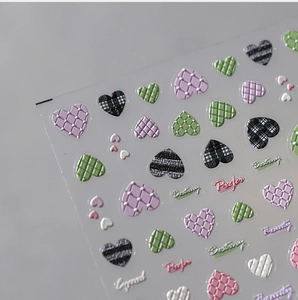 Macro shot of 3D embossed heart nail art stickers with quilted texture and text