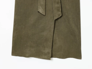 Detalle de gabardina verde militar de ante sintético con costuras y cinturón de lazo