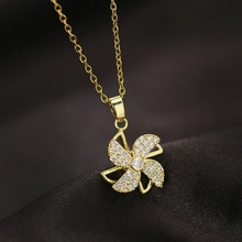 Detailed close-up of golden windmill pendant with sparkling diamonds on a soft dark fabric