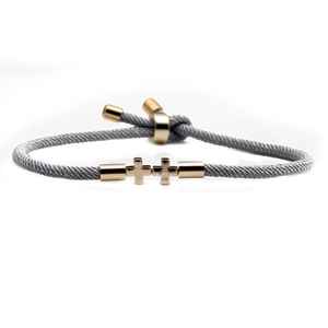 Adjustable gray woven rope bracelet featuring two polished gold interlocking crosses