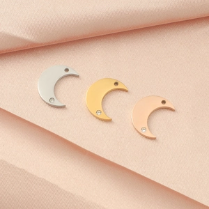 Macro detail of crescent moon pendants with crystal accents in silver, gold, and rose gold