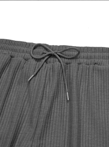 Detail view of grey vertical stripe trousers featuring elastic waistband and metal tip drawstring