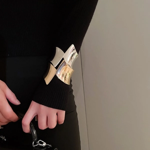 Dettaglio dell'ampio bracciale aperto caratterizzato dal design bicolore oro e argento