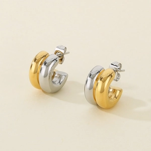 Detail of C-shaped stainless steel earrings in dual-tone gold and silver metallic finish