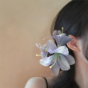 Detail view of a 3D purple lily hair claw clip worn on a bun for elegant hairstyling