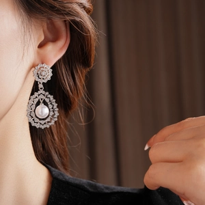 Close-up of vintage flower-shaped earrings with pearls and crystals on a model