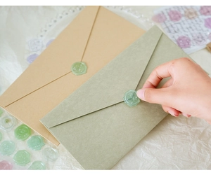 Close-up of translucent wax seal stickers being applied to envelopes for scrapbooking