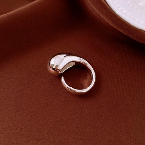 Close-up of a silver droplet ring with a streamlined design on brown velvet texture