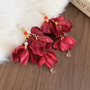 Detailaufnahme der Vintage-Blumenohrringe mit roten Blütenblättern auf weißem Kunstpelz